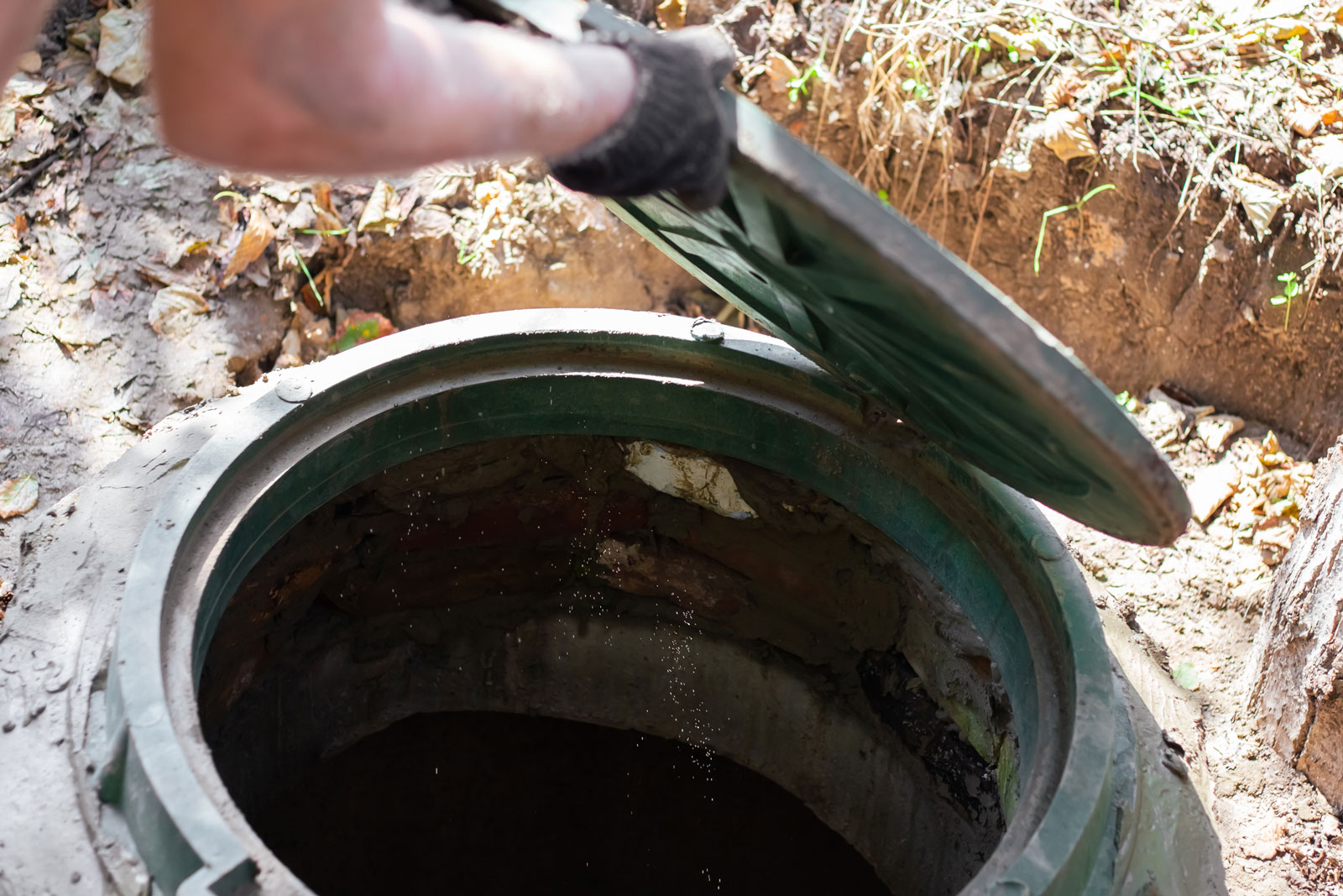 Skilled technician opening a sewer hatch for septic tank inspection and maintenance